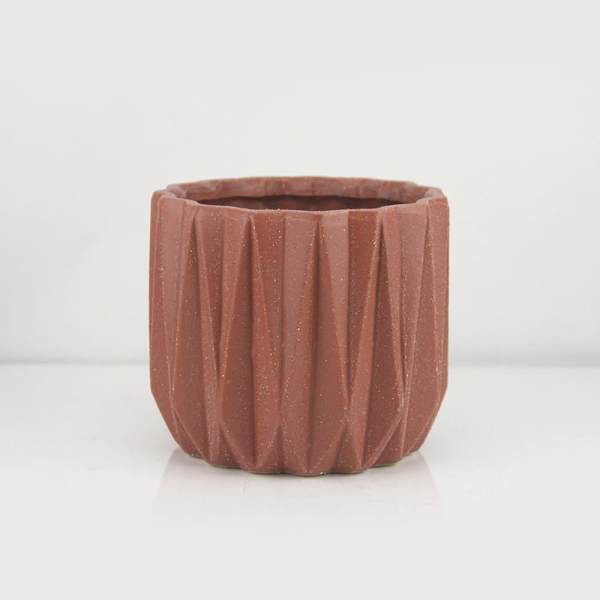 Textured terracotta-colored planter pot on a white background