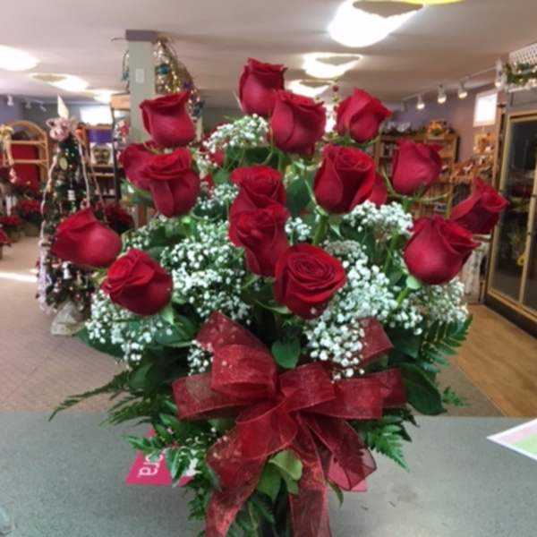 Red roses arranged in a clear vase with a red ribbon bow