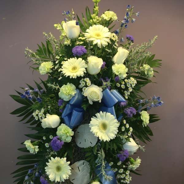 Standing floral spray with white roses and gerbera daisies, blue ribbon accents