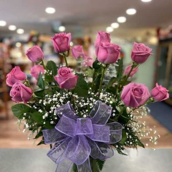 Pink roses in a glass vase with a purple bow
