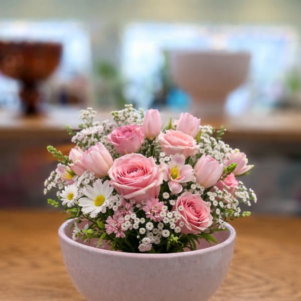 Pink roses and tulips arranged in a pale ceramic bowl