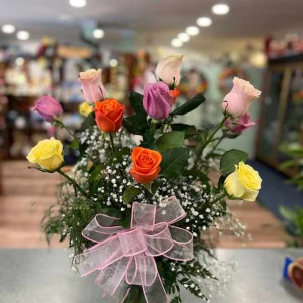 Mixed roses in a glass vase with a pink ribbon bow