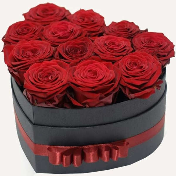 Red roses arranged in a black heart-shaped box with a red ribbon
