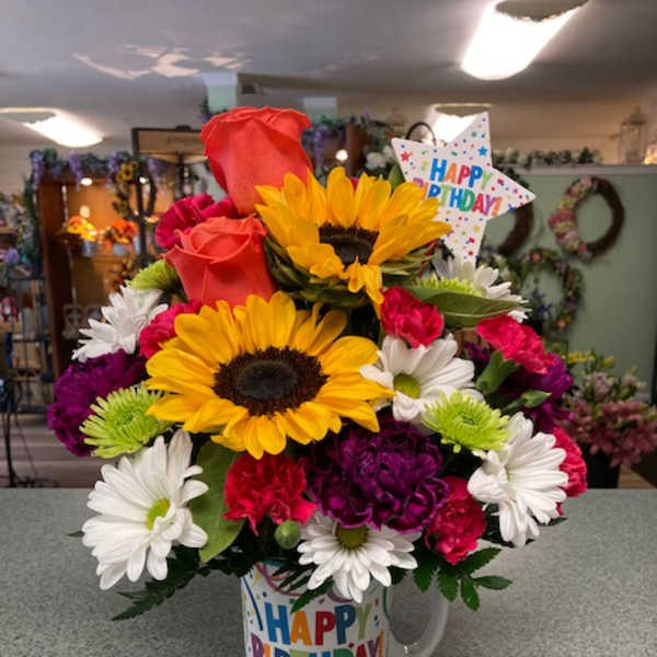 Birthday bouquet with sunflowers, roses, daisies, and carnations in a mug