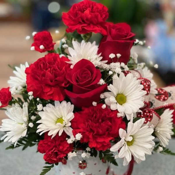 Red roses and white daisies in a patterned mug