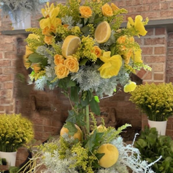 Yellow floral arrangement in a blue-and-white ceramic vase with citrus slices.