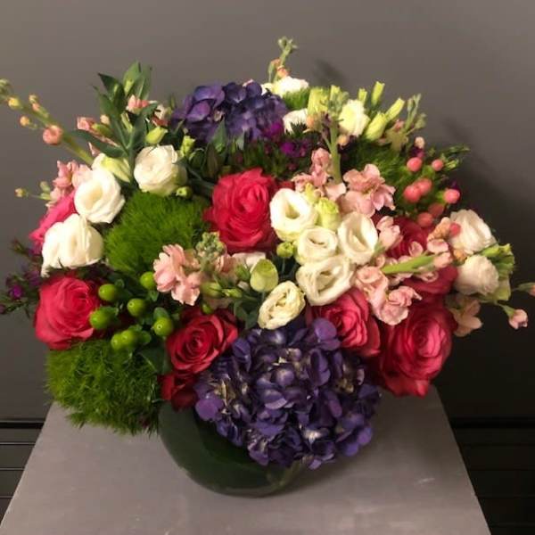 Mixed bouquet of roses, hydrangeas, and pink blooms in a vase