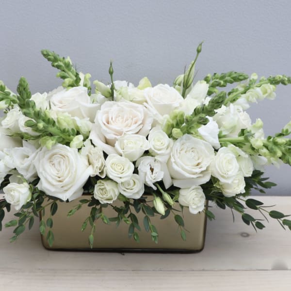 White roses and snapdragons arranged in a rectangular vase