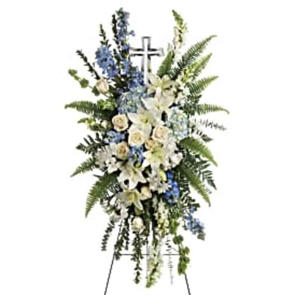 Standing funeral spray with white lilies, blue flowers, and a cross