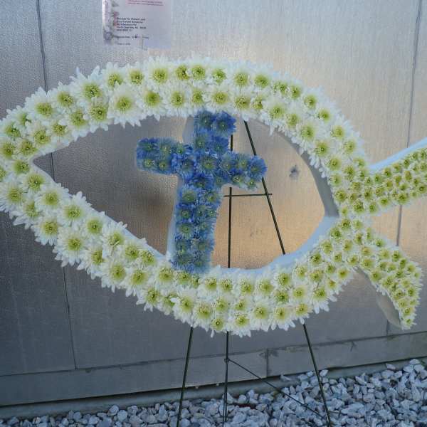 Fish-shaped floral tribute with white and blue flowers on a stand