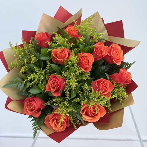 Bouquet of orange roses wrapped in red and gold paper