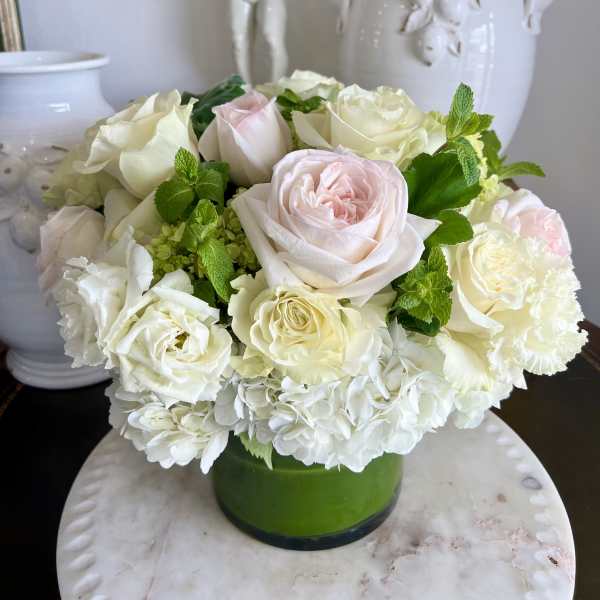 White and pale pink roses arranged in a green vase