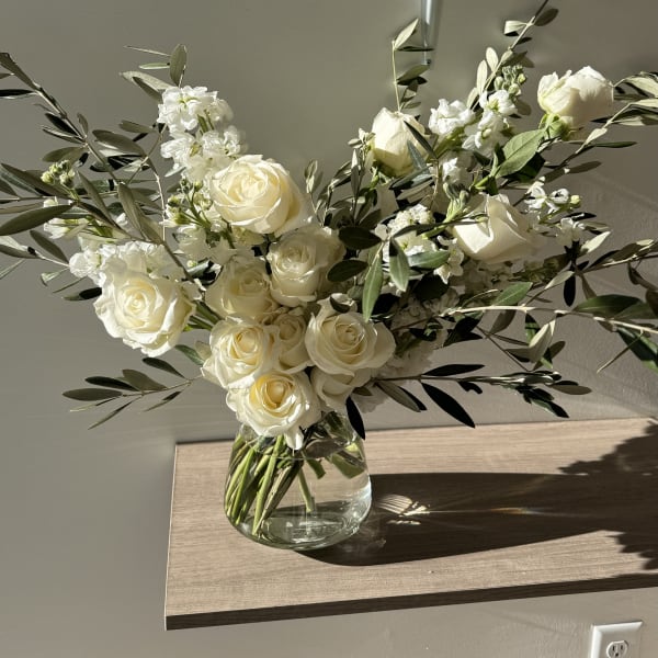 White roses and small white flowers in a clear glass vase