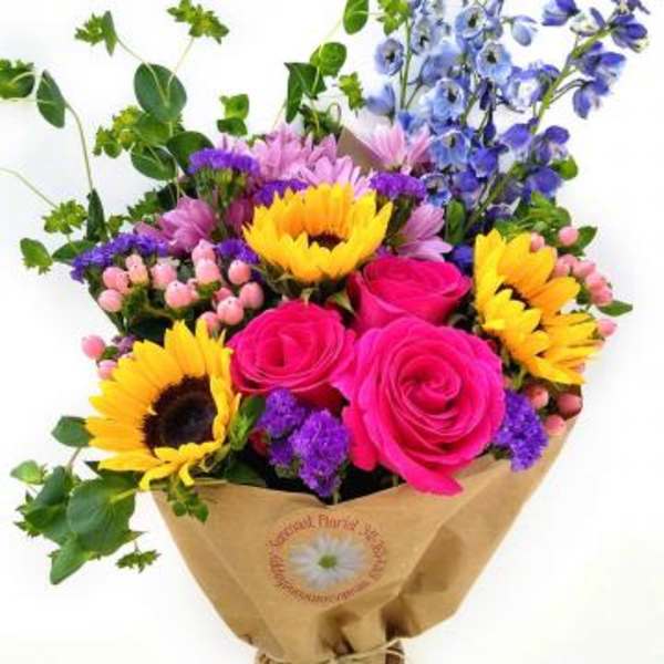 Bouquet of pink roses, sunflowers, and blue flowers wrapped in brown paper
