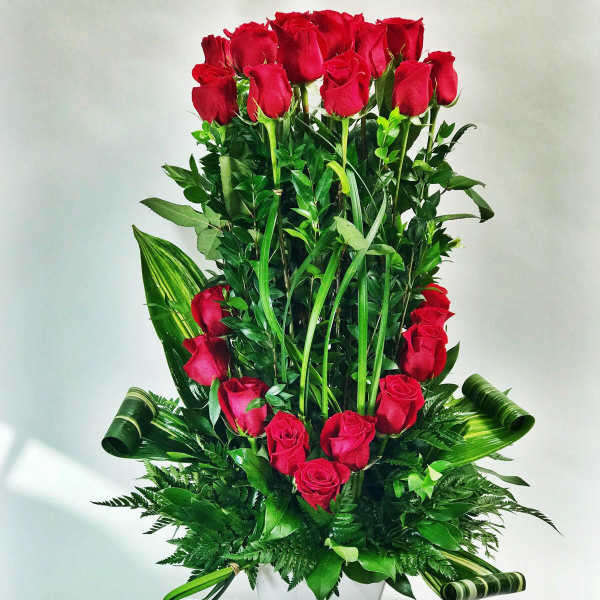 Tall arrangement of red roses in a white vase