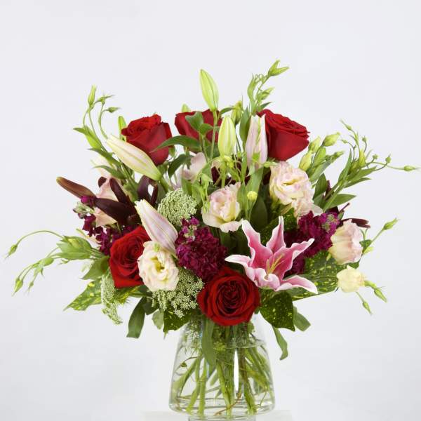Bouquet of red roses and pink lilies in a clear glass vase