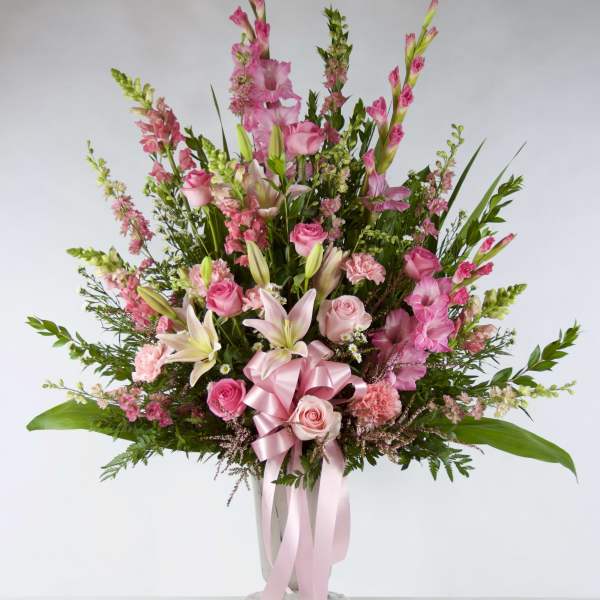 Tall pink floral arrangement in a vase with a pink ribbon bow