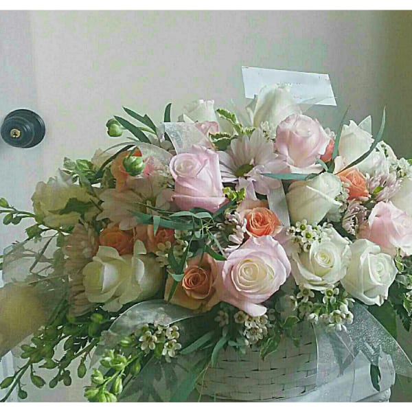 Pastel roses and white blooms arranged in a white basket