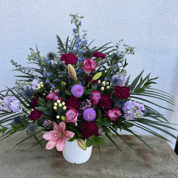 Mixed pink, purple, and blue floral arrangement in a white vase