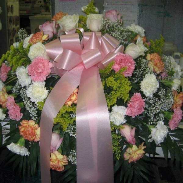 Large floral wreath with pink ribbon and mixed pink, white, and peach flowers