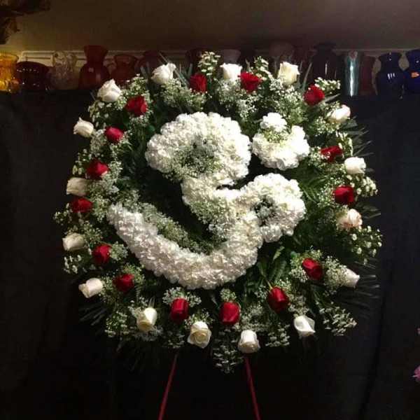 Large funeral wreath with white and red roses on a stand