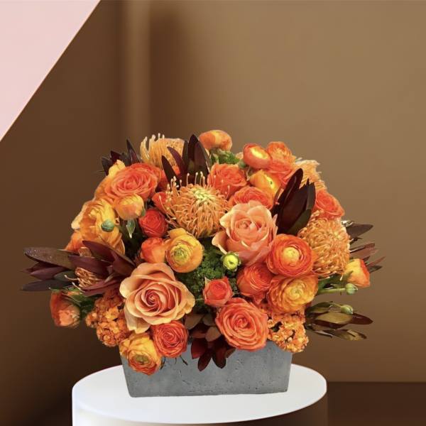Orange and peach roses in a gray rectangular vase