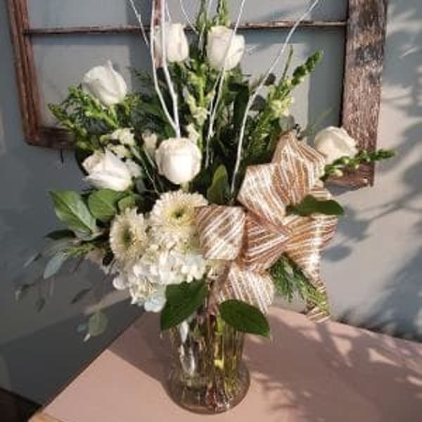 White tulips and cream flowers in a glass vase with striped ribbon