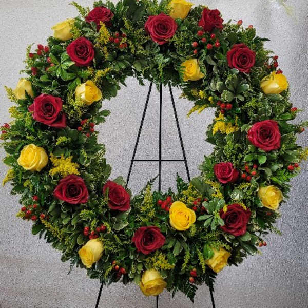 Heart-shaped wreath of red and yellow roses on an easel
