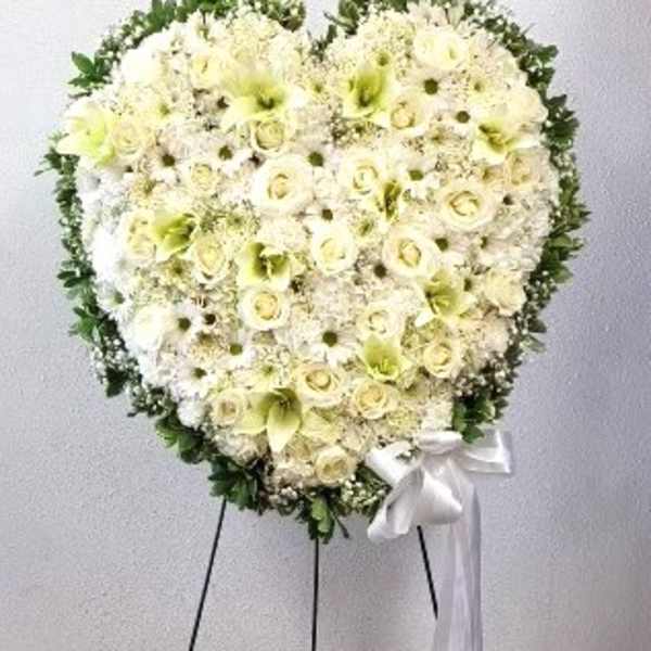 Heart-shaped white floral standing spray with a white ribbon
