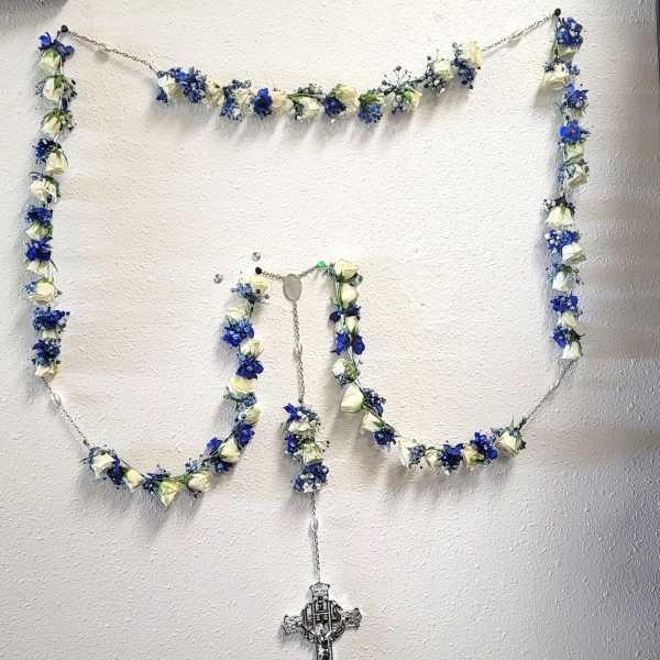 Blue and white floral garland arranged in a rosary shape with a cross pendant