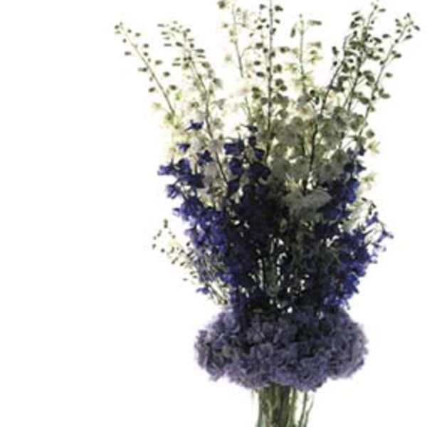 Tall bouquet of purple and white flowers in a clear vase