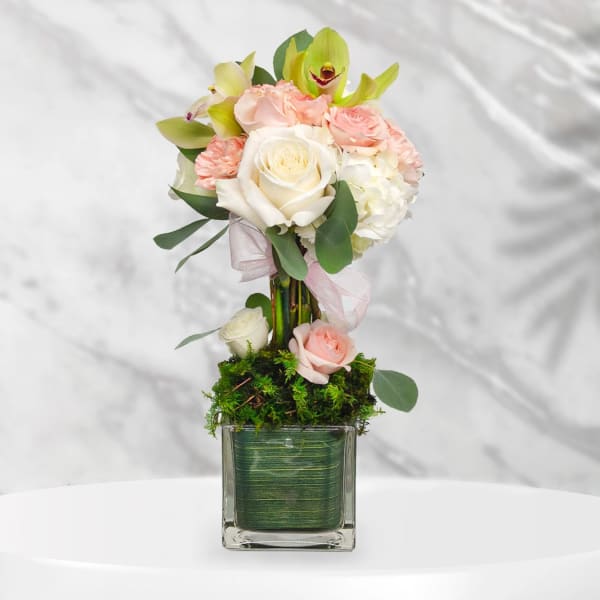 Pink and white rose arrangement in a square glass vase