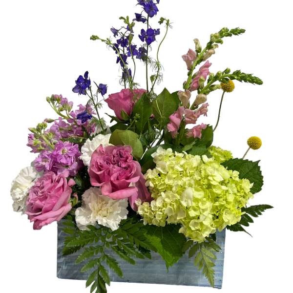 Mixed pink, purple, and green floral arrangement in a rectangular container