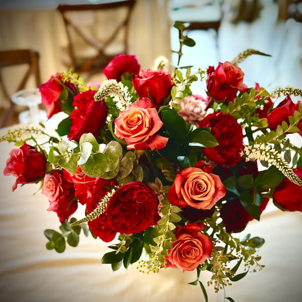 Rounded arrangement of red and orange roses on a table