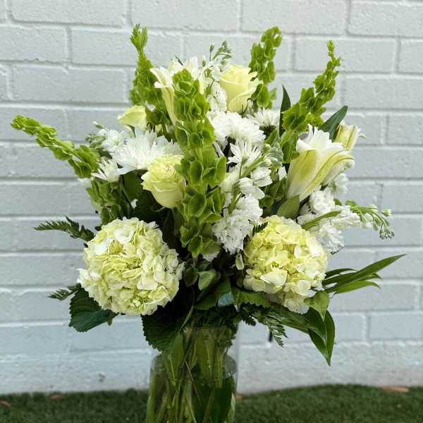 White and pale green floral arrangement in a glass vase