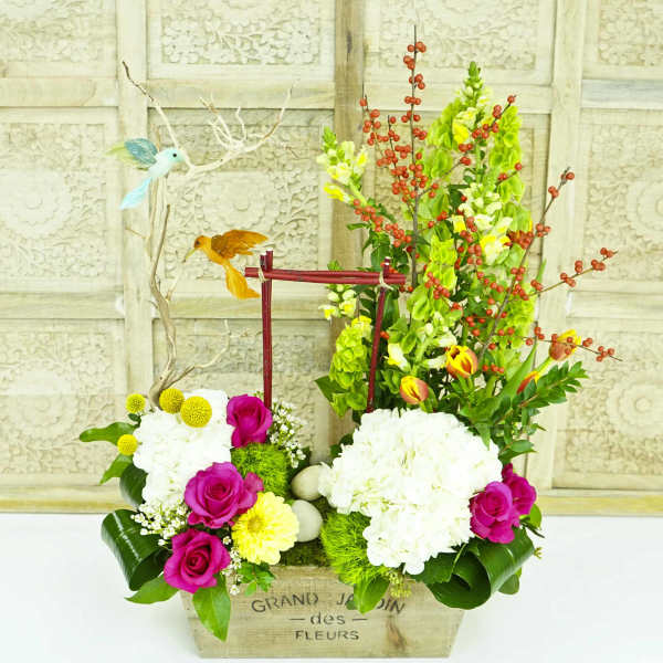 Floral arrangement with pink roses, white hydrangeas, and red berry branches in a wooden box