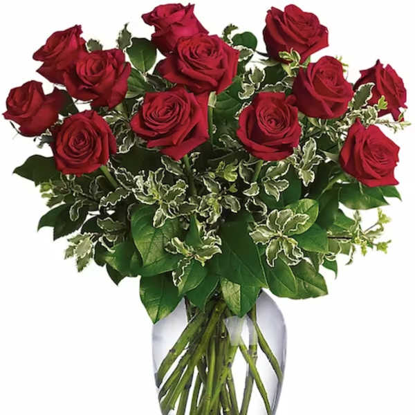 Red roses arranged in a clear glass vase with mixed greenery