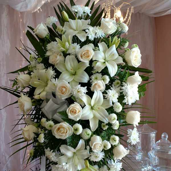 Large white floral standing spray on an easel with ribbon