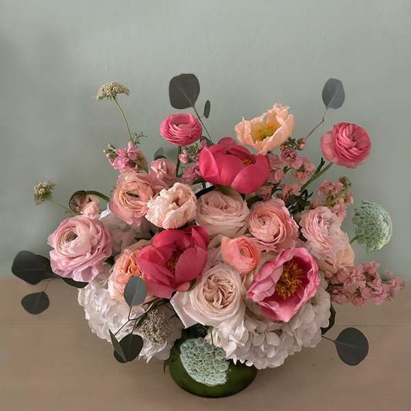 Pink and blush floral arrangement in a green vase