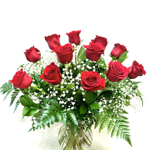 Dozen red roses with white filler flowers arranged in a clear glass vase