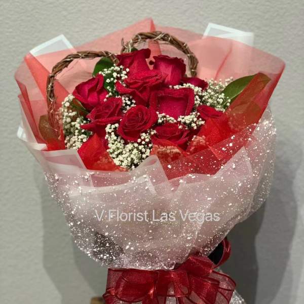 Bouquet of red roses wrapped in pink and white mesh with a red ribbon