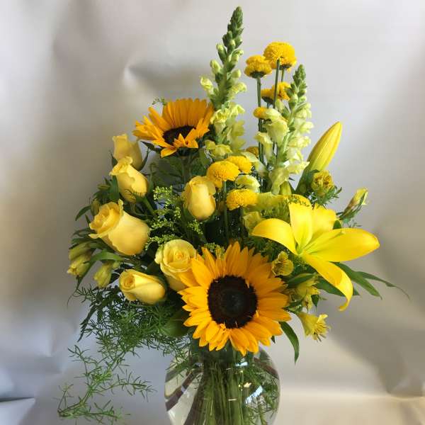 Yellow bouquet with sunflowers and roses in a glass vase