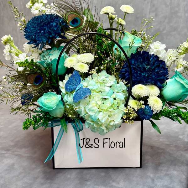 Blue and white floral arrangement in a white gift box with peacock feathers
