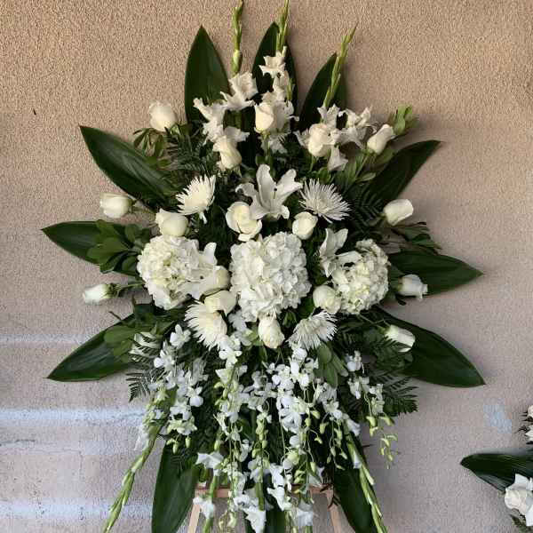 White funeral spray with roses, lilies, and orchids on an easel