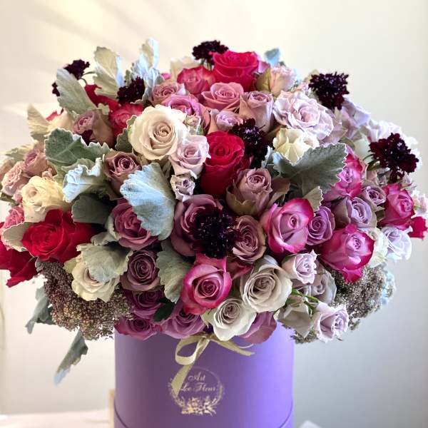 Bouquet of pink, lavender, and white roses in a purple hat box