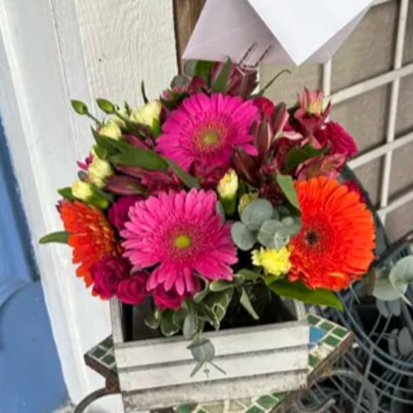 Bright mixed bouquet with pink and orange daisies in a white box