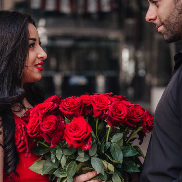 Couple holding a large bouquet of red roses