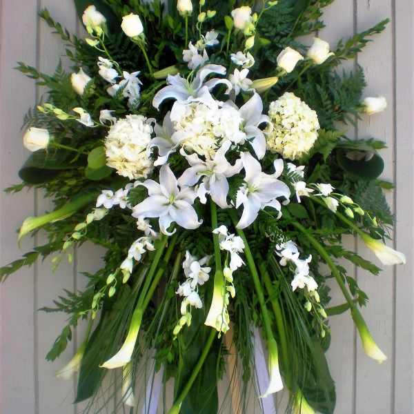 White floral standing spray with lilies, roses, and orchids