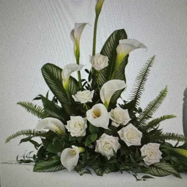 White calla lilies and roses arranged with dark greenery