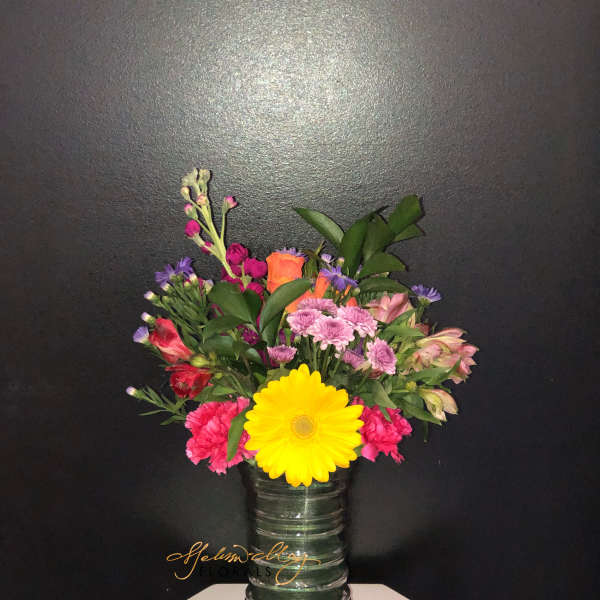Mixed bouquet in a glass vase with a large yellow daisy and pink flowers